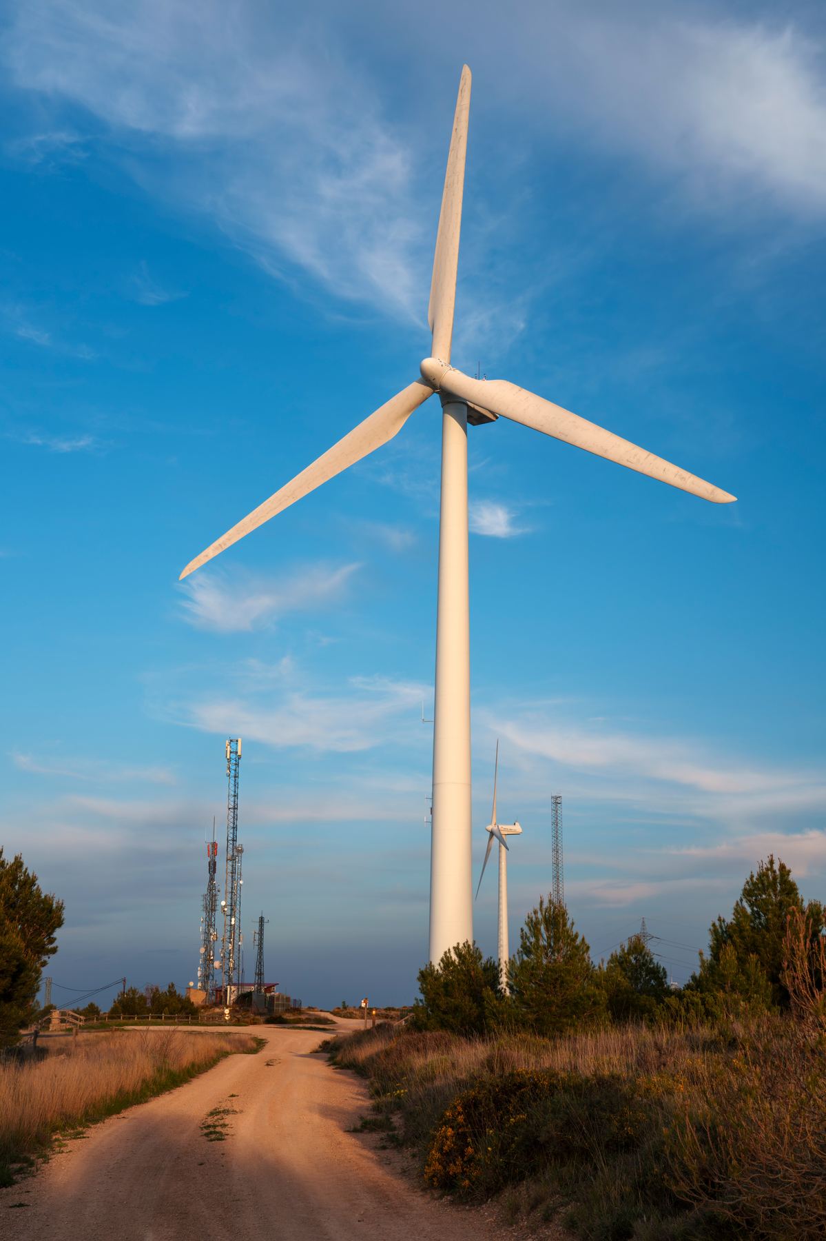 Wind turbine and cell towers on a rural property with a dirt access road